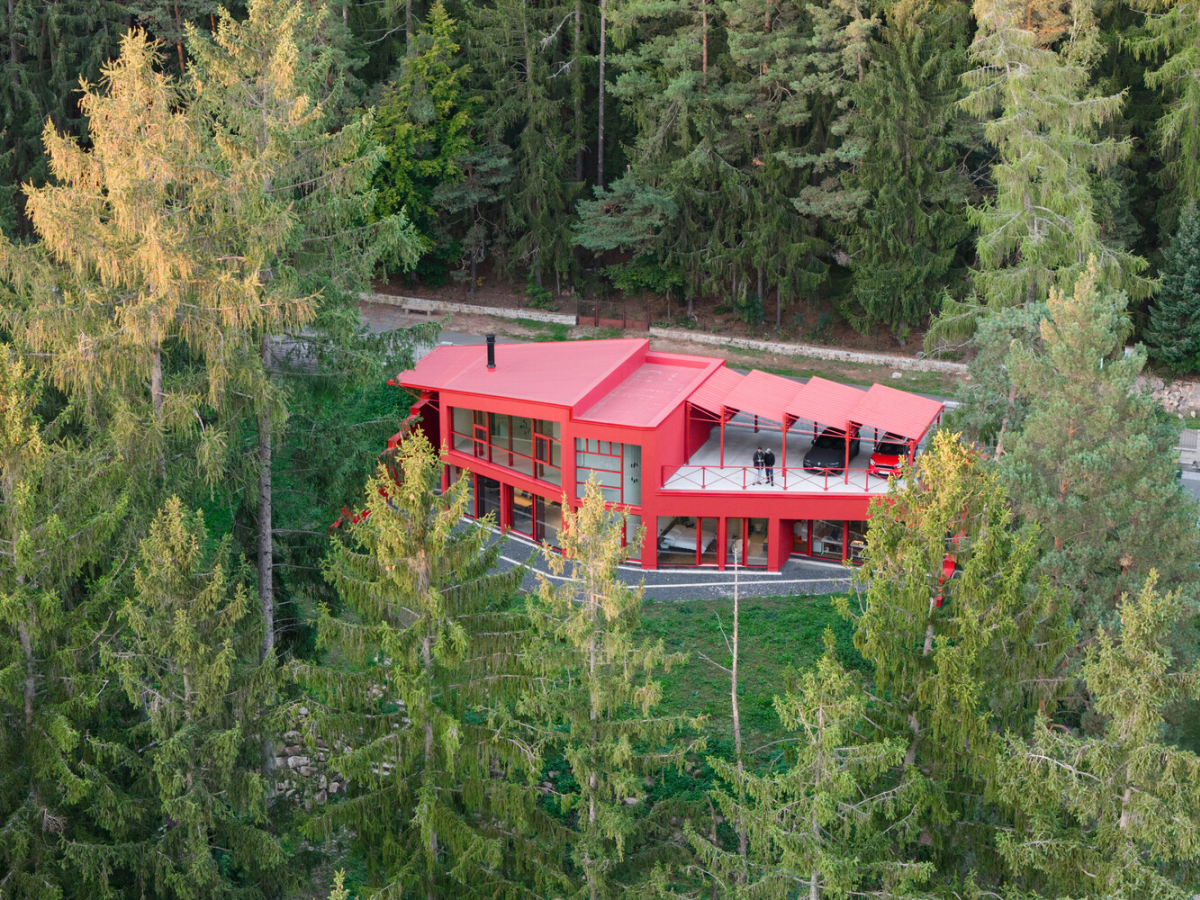 Biệt thự màu đỏ nổi bật giữa rừng, xe đỗ trên mái nhà